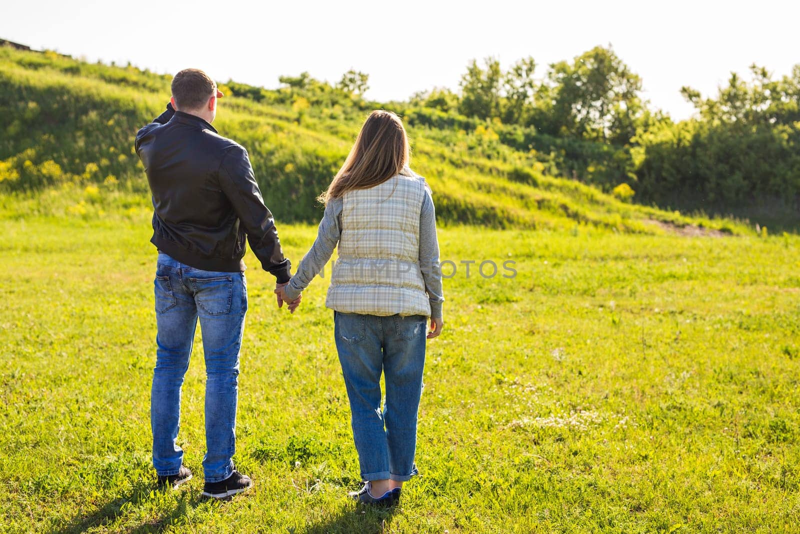rear view of couple holding hands walking in autumn countryside by Satura86