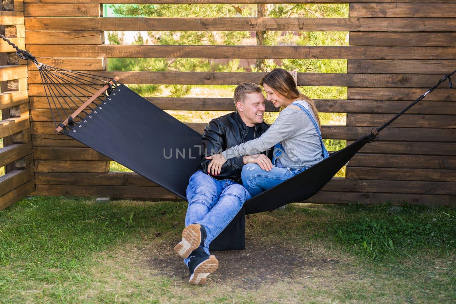 Expectant young loving couple on hammock outdoors