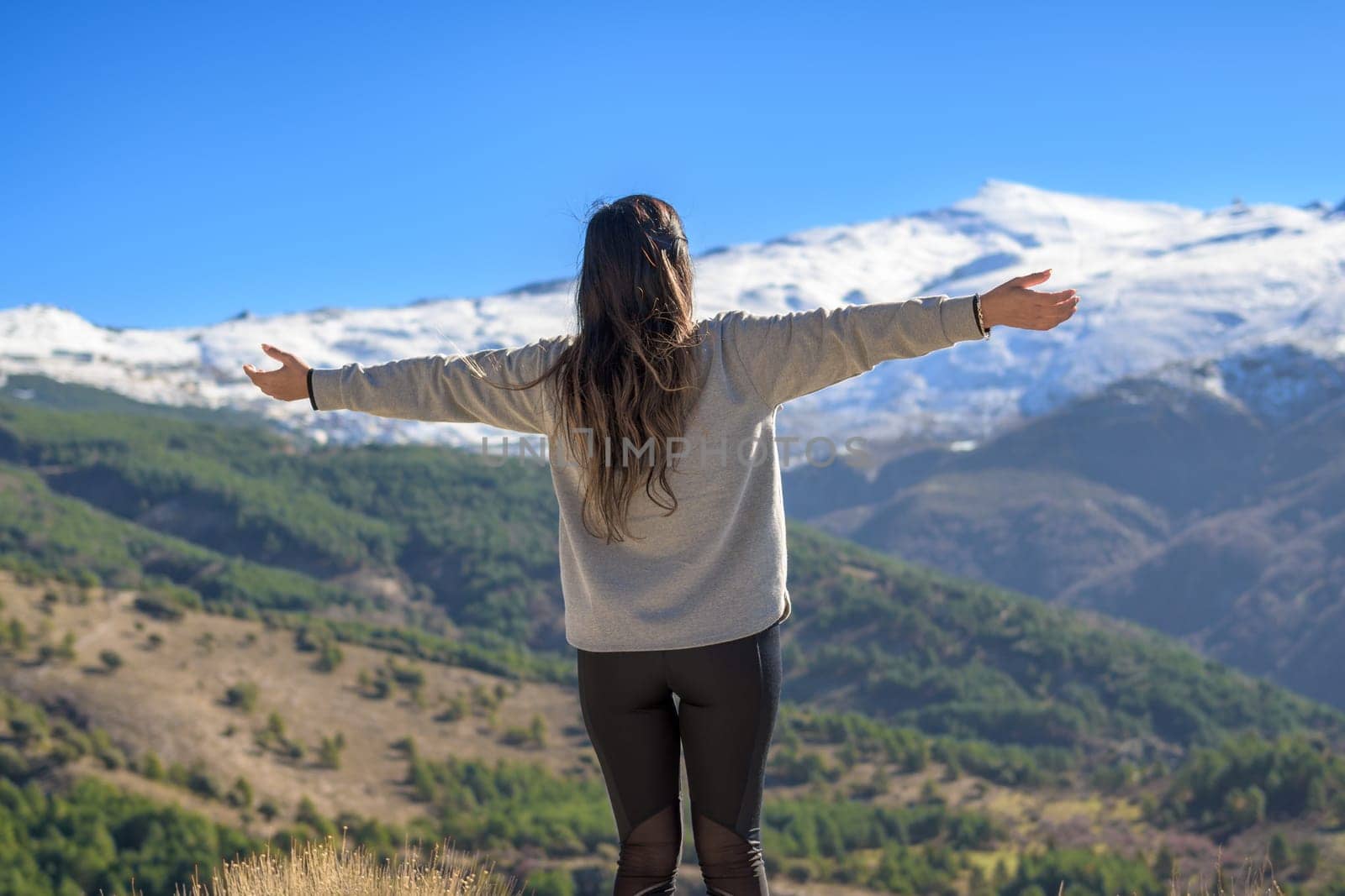 Hiker on her back with arms outstretched happily enjoying the scenery while walking outdoors in winter by carlosviv