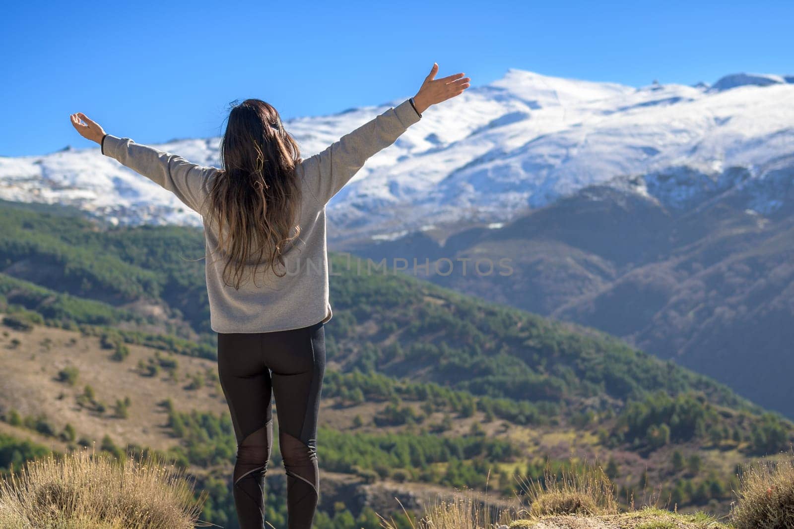 Latina woman on her back with arms outstretched happily enjoying the scenery outdoors in winter. by carlosviv