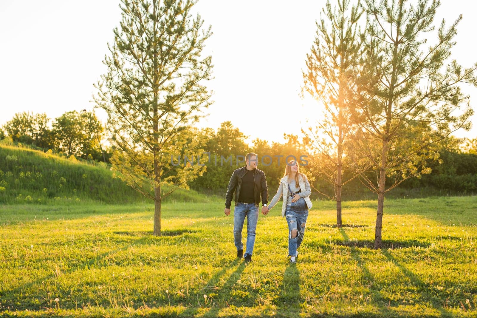 Happy couple awaiting baby, cute pregnant woman with husband enjoying spring weather, love concept.