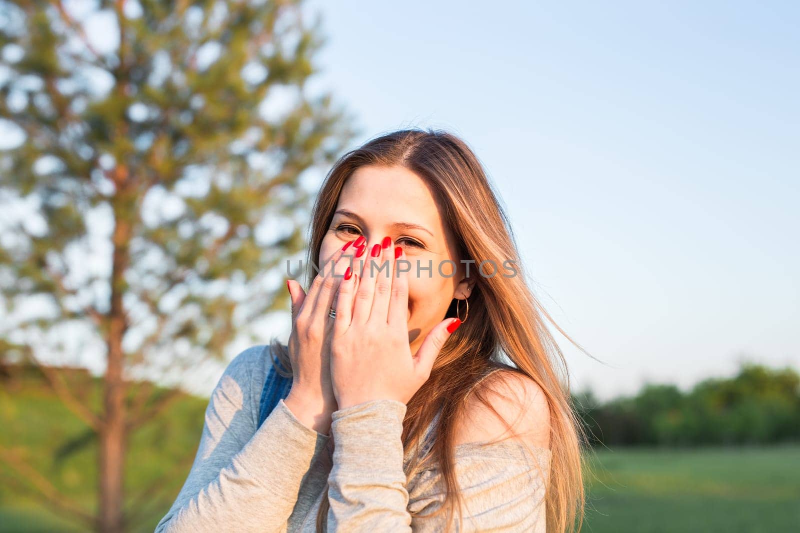 Surprised young woman with hands over her mouth outdoor.