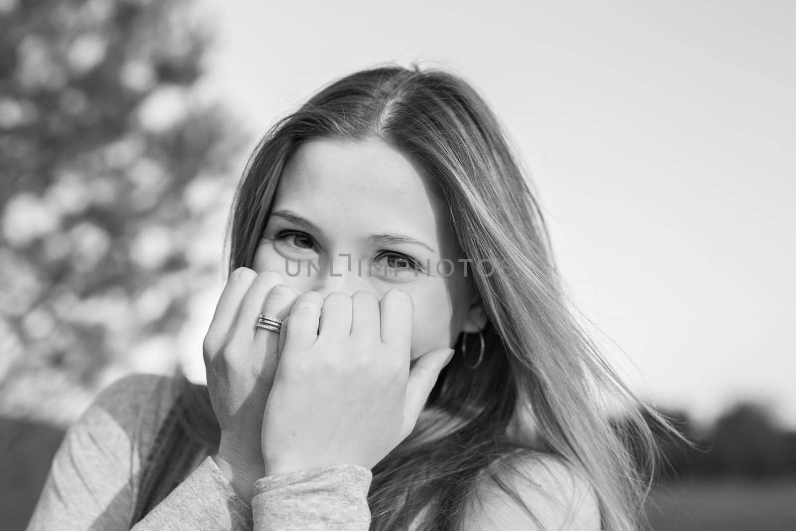 Surprised young woman with hands over her mouth outdoor.