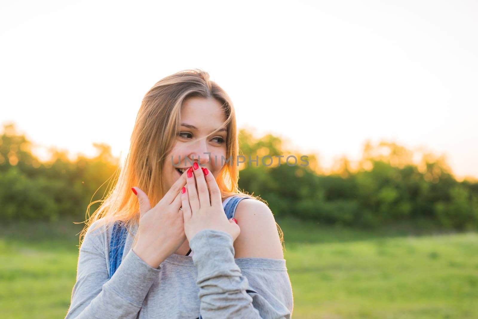 Surprised young woman with hands over her mouth outdoor by Satura86