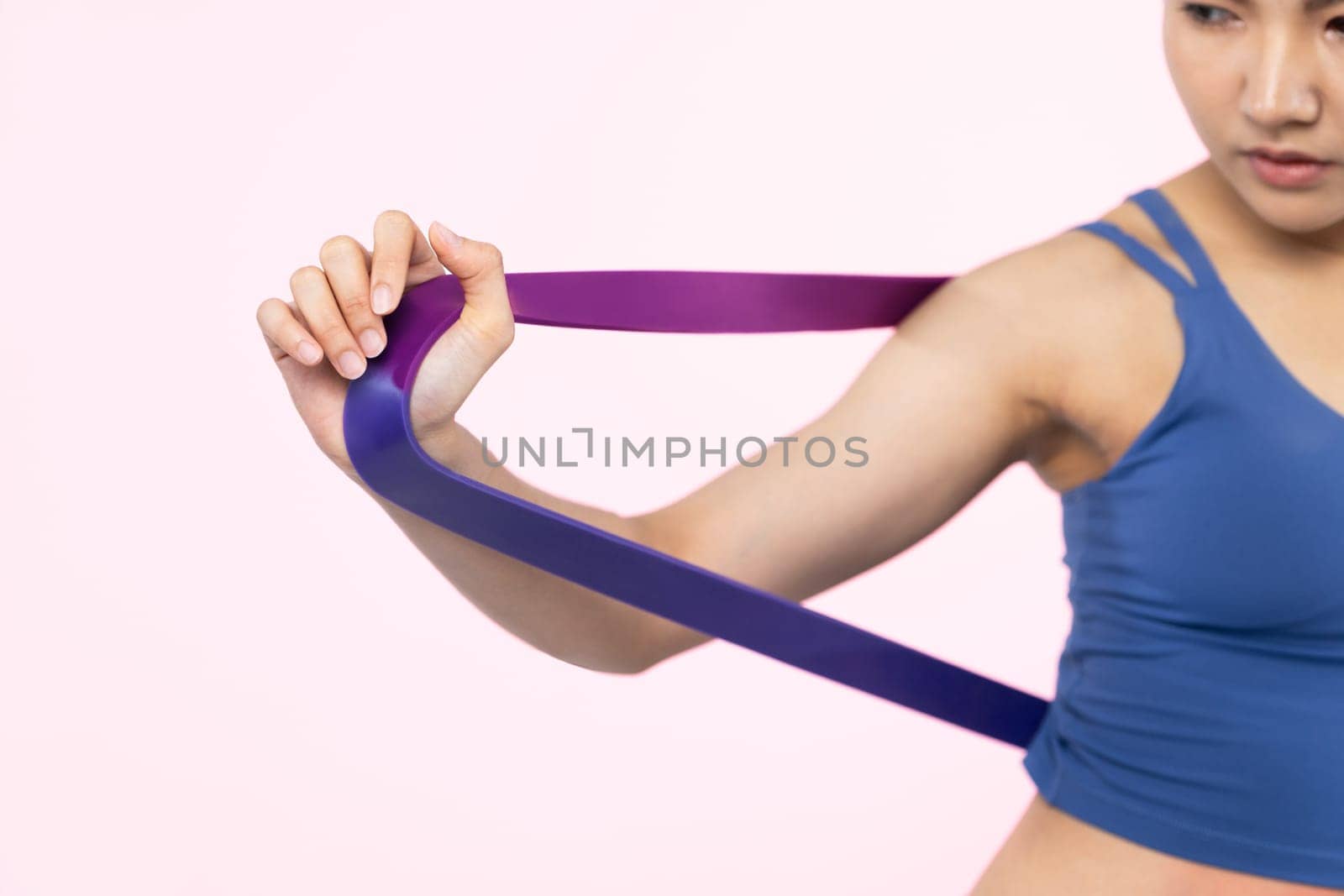 Vigorous energetic woman in sportswear portrait stretching resistance sport band. Young athletic asian woman strength and endurance training session workout routine concept on isolated background.