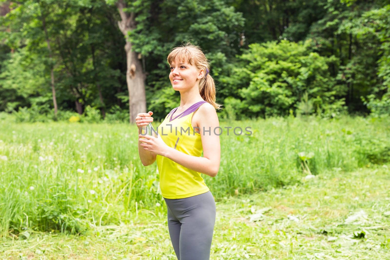 Fitness woman drinking water after work out exercising on summer outdoor portrait by Satura86