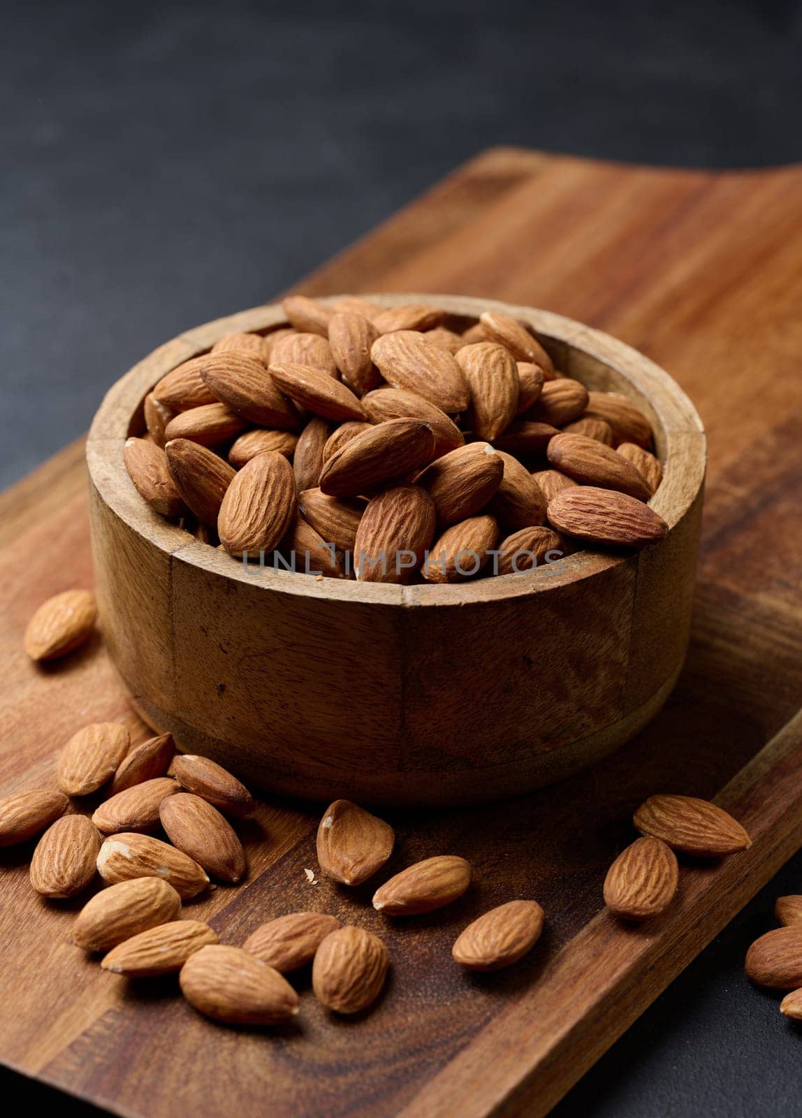 Peeled almond kernels in a round wooden plate on the table