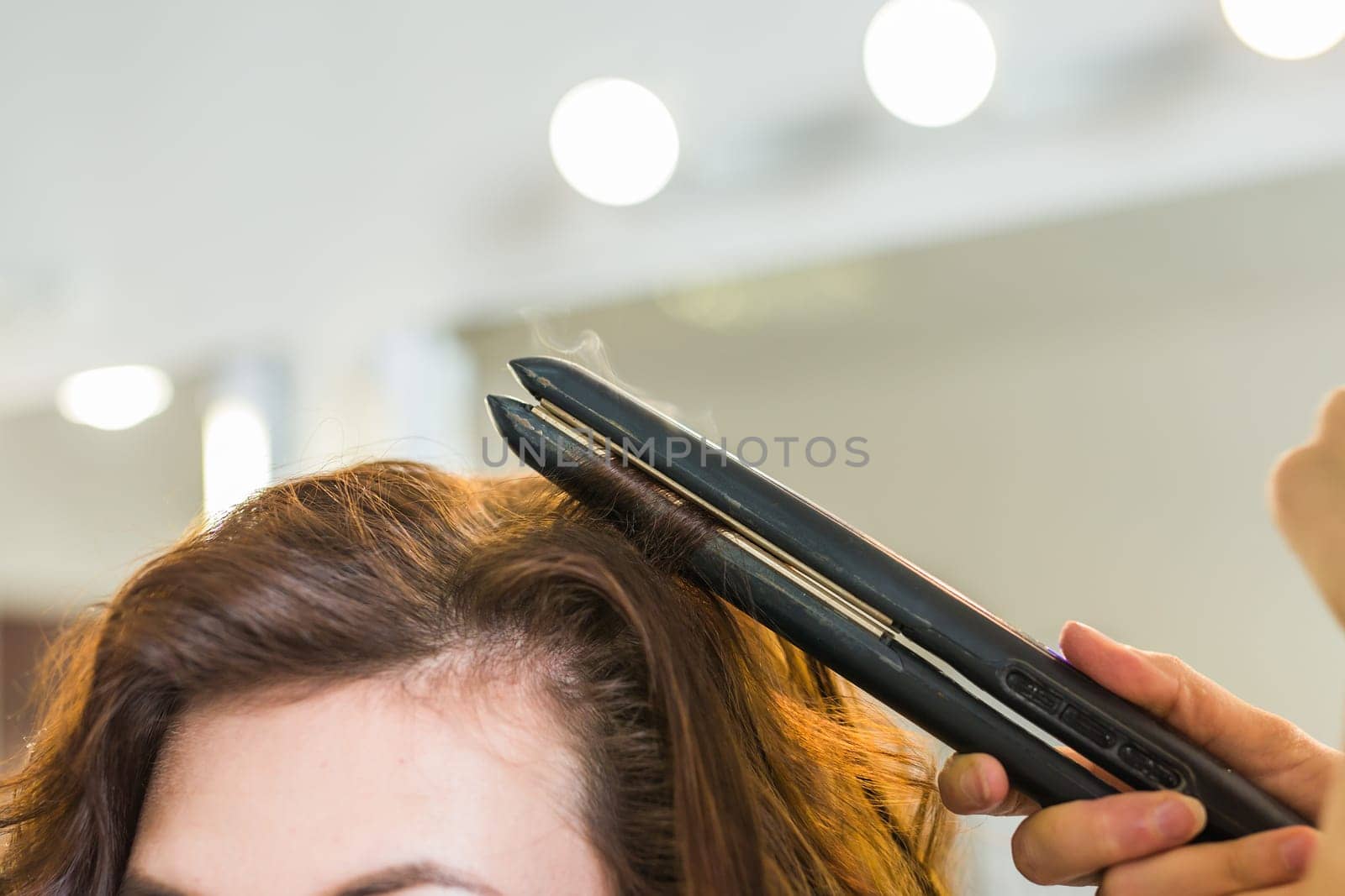 Close up of stylist's hand using curling iron for hair curls. by Satura86