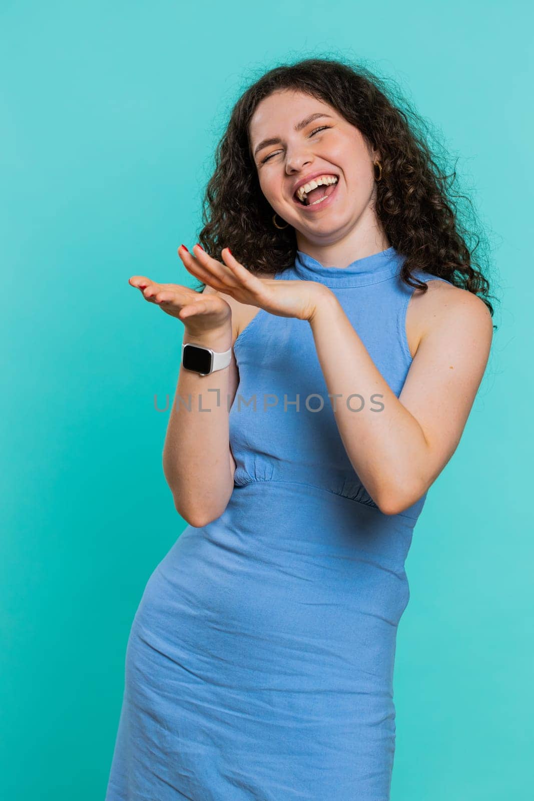 Young woman showing wasting, throwing money around, more tips, big profit, winning lottery jackpot, successful shopping payment purchase, cashback. Girl isolated on blue studio background. Vertical