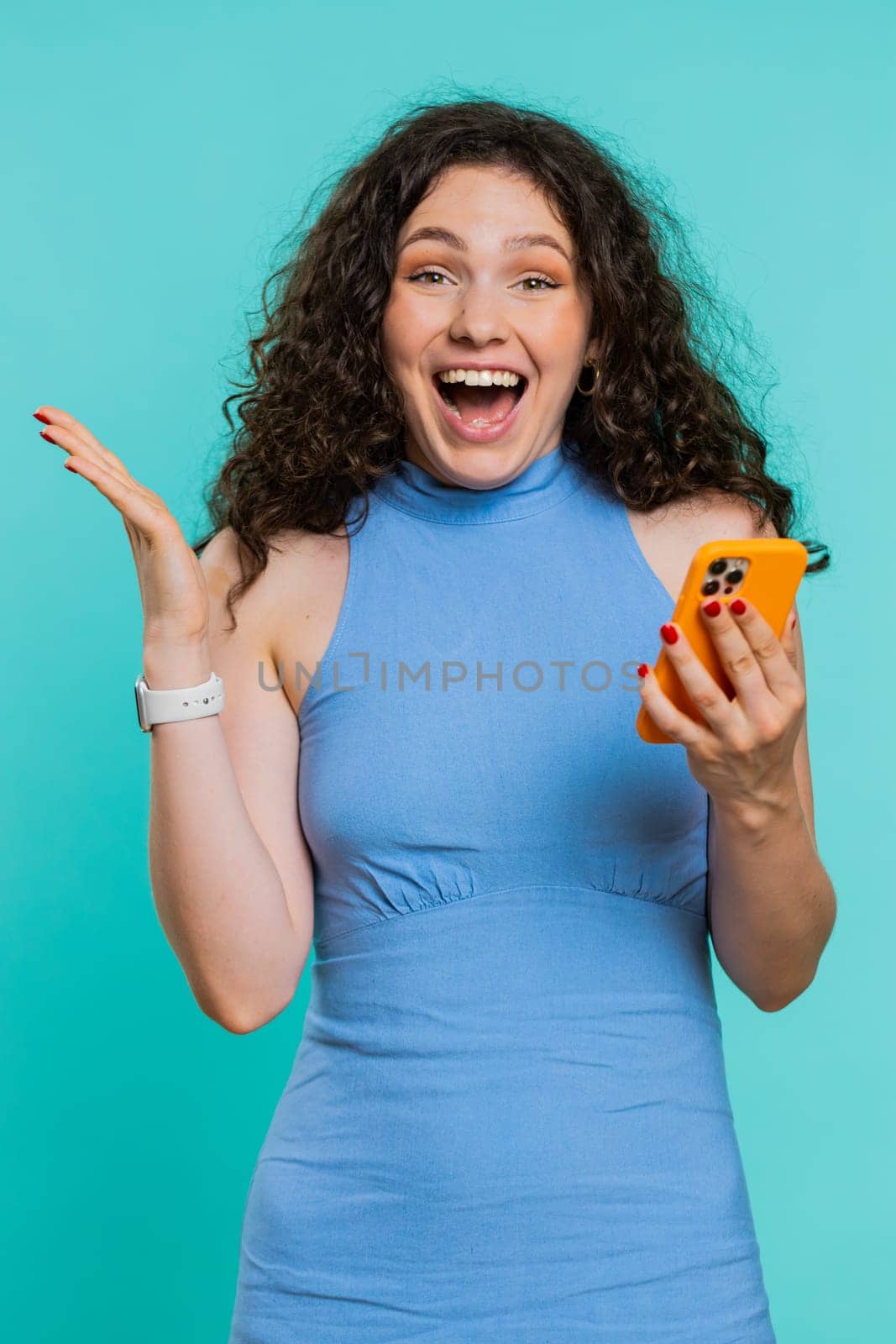Happy excited woman girl use smartphone typing browsing shouting say wow yes found out great big win, good news, lottery goal achievemen, celebrating success, winning game on blue background. Vertical