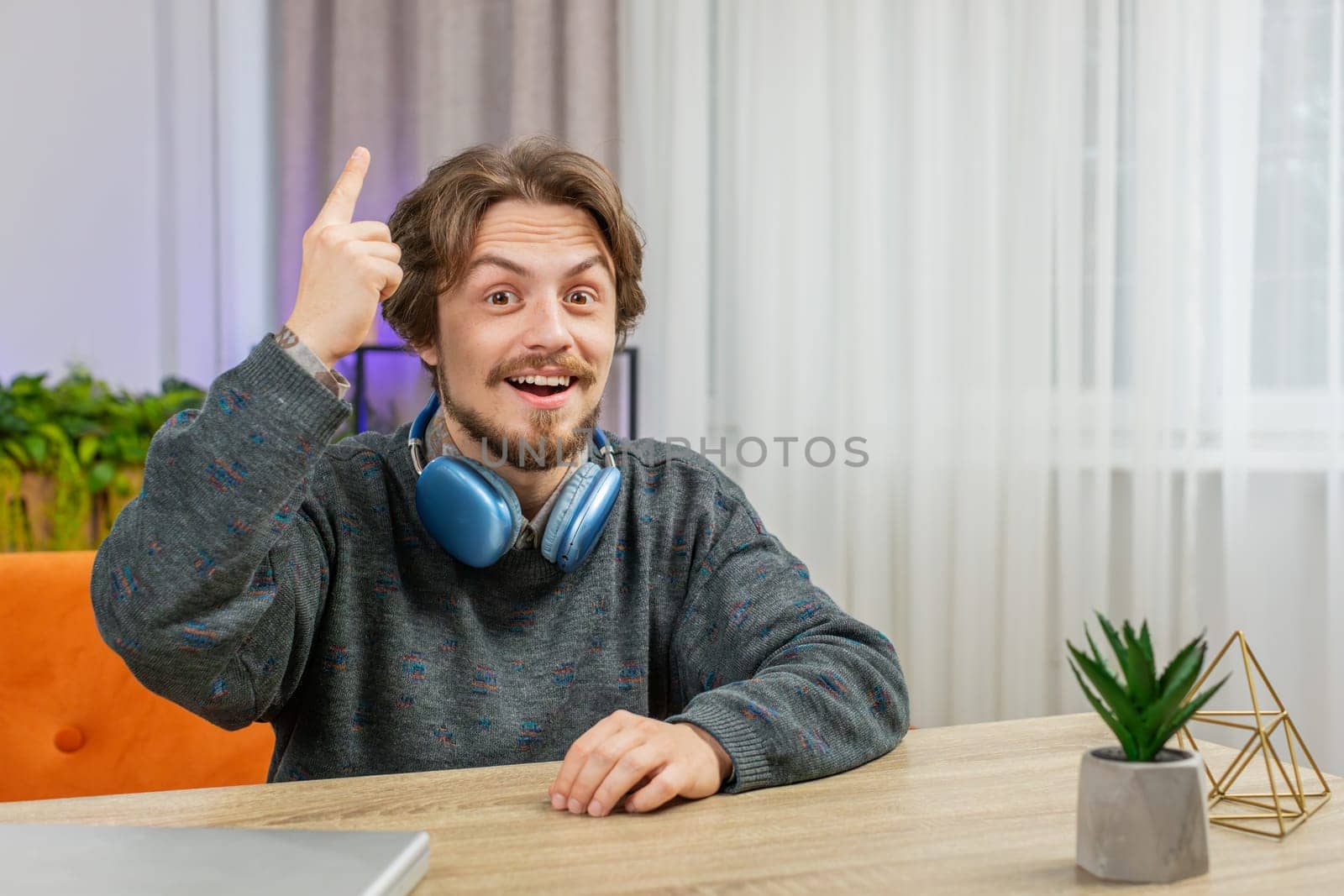 Eureka. Thoughtful clever inspired Caucasian man make gesture raises finger came up with creative plan feels excited with good idea inspiration motivation question at home apartment. Guy sits at desk