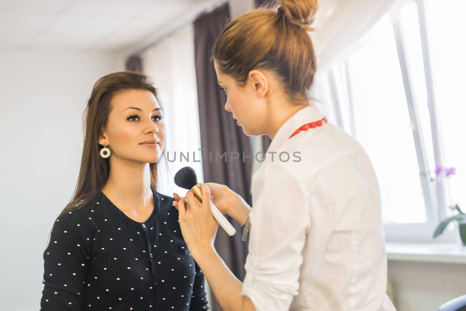 Make-up artist doing make up for young beautiful woman.
