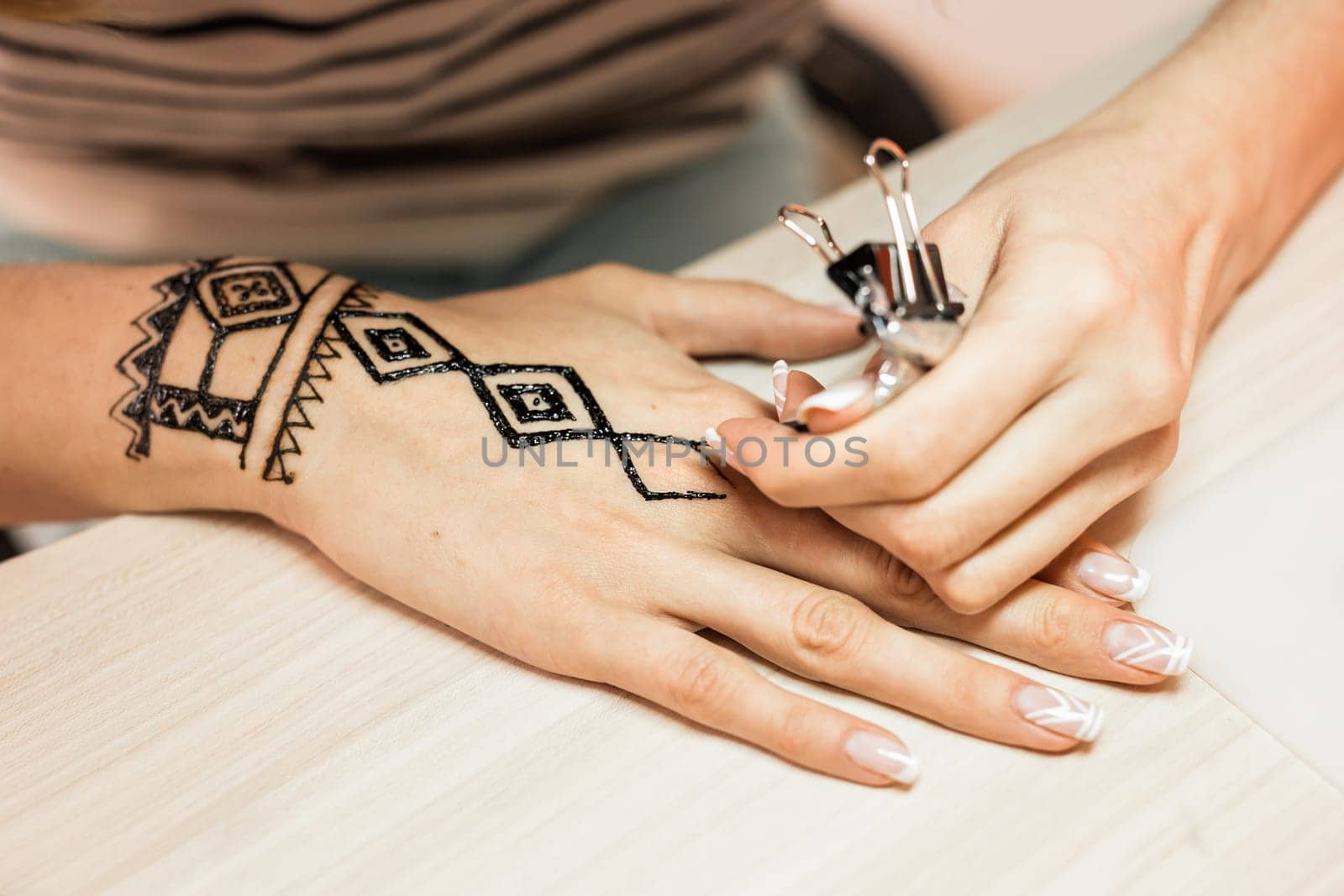 Artist applying henna tattoo on women hands. Mehndi is traditional Indian decorative art. Close-up by Satura86