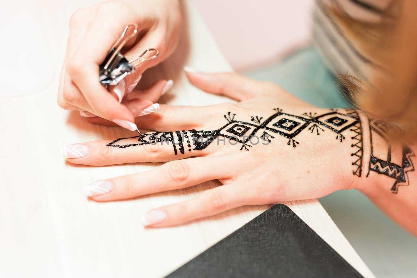 Artist applying henna tattoo on women hands. Mehndi is traditional Indian decorative art. Close-up by Satura86