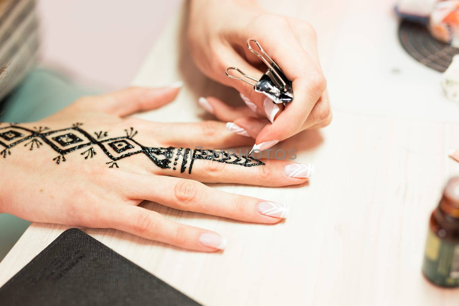 Artist applying henna tattoo on women hands. Mehndi is traditional Indian decorative art. Close-up.