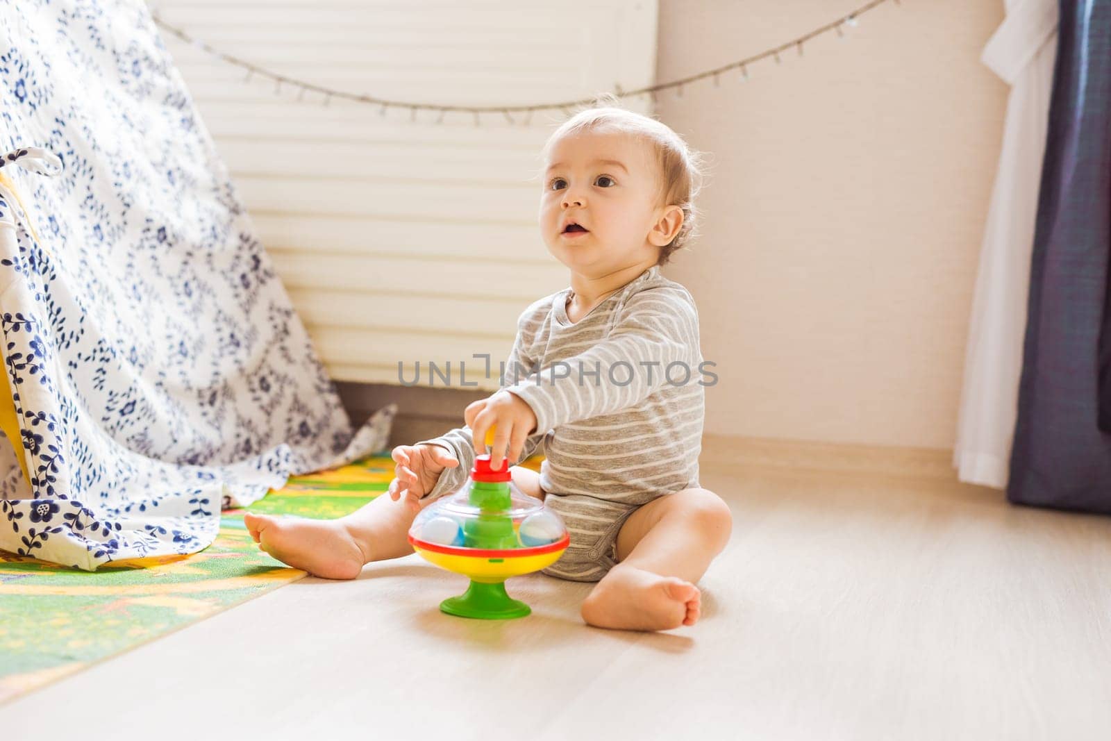 baby boy playing with toy indoors at home.