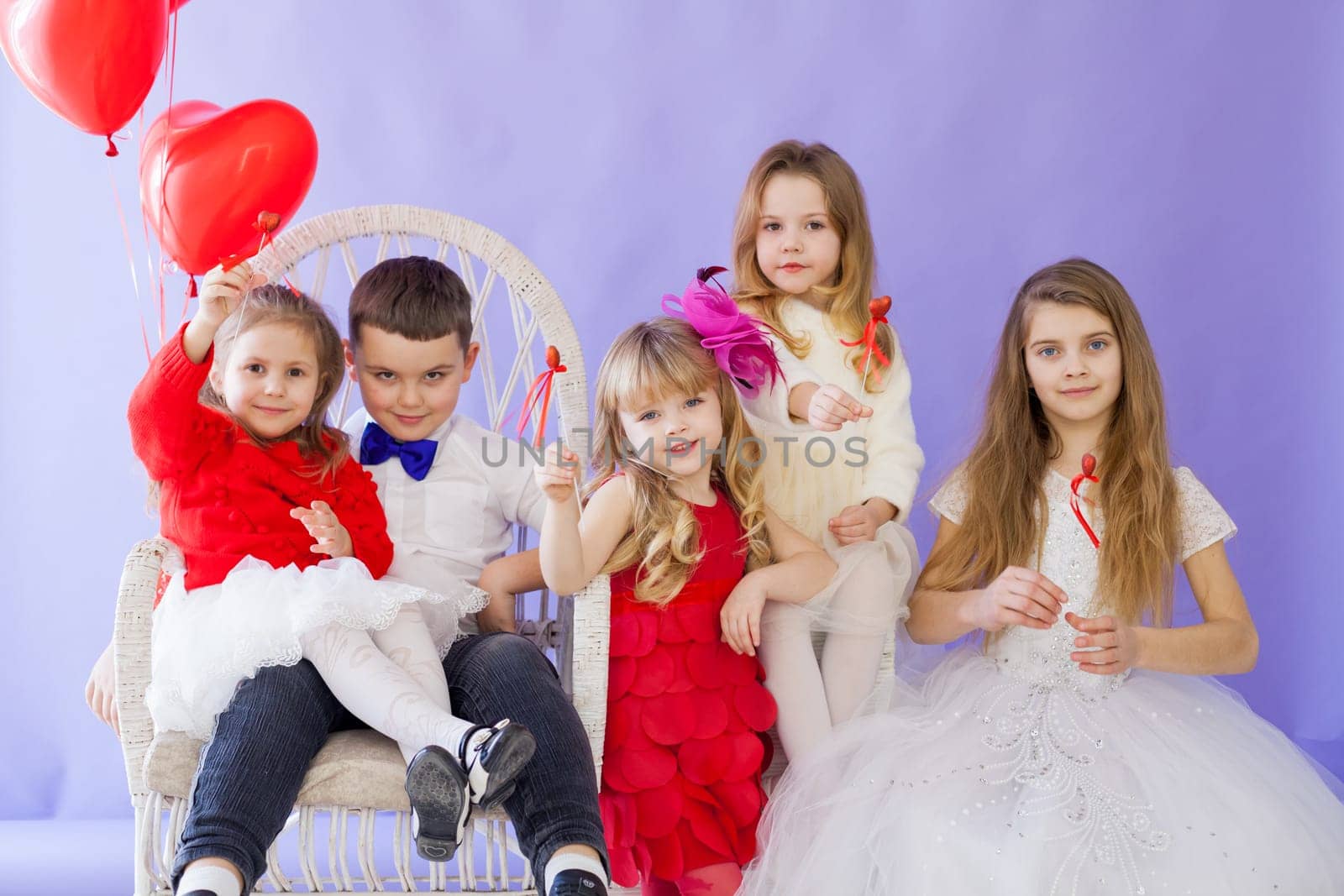 Boy and girls sit together with red balloons by Simakov