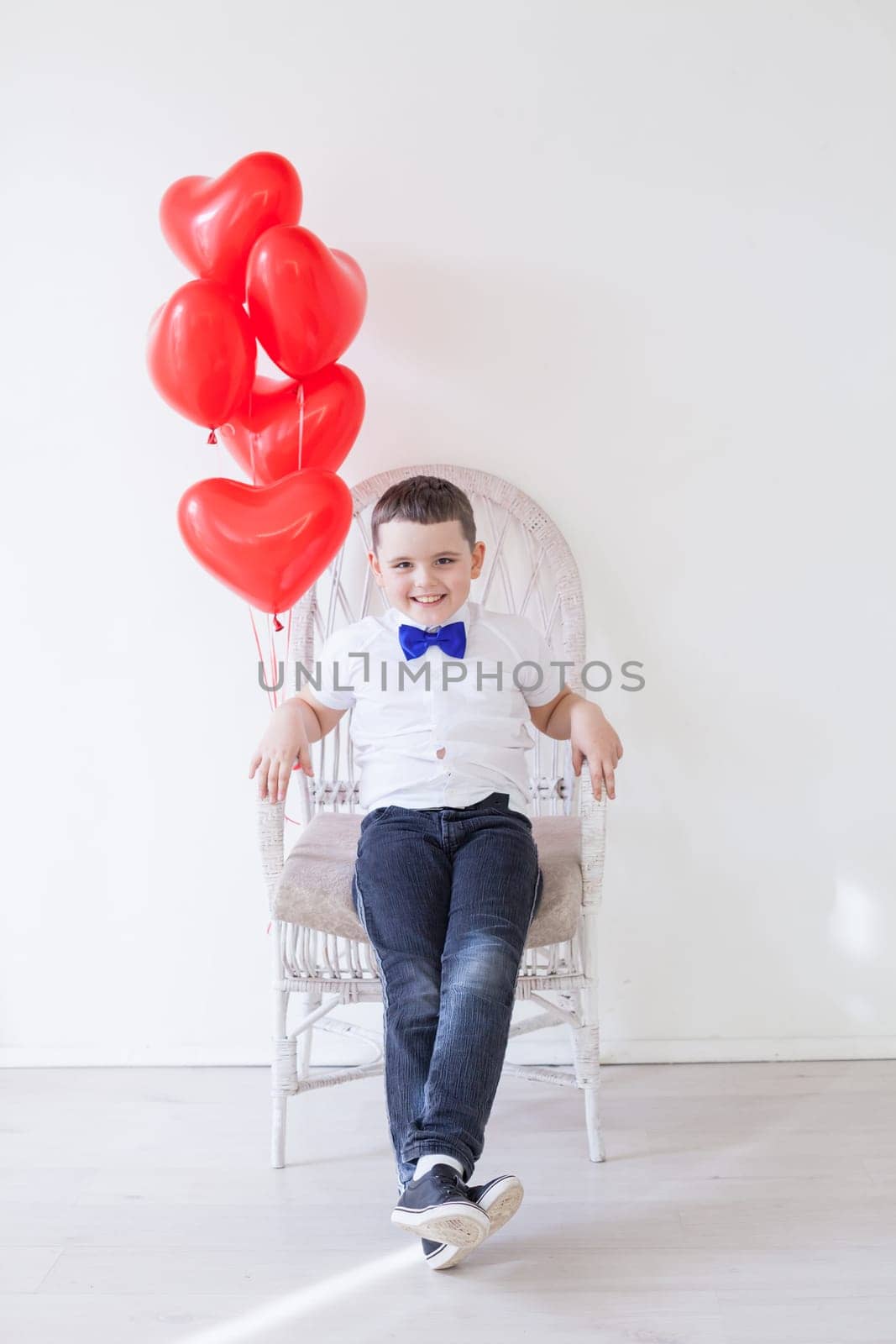 boy sits with red heart balloons