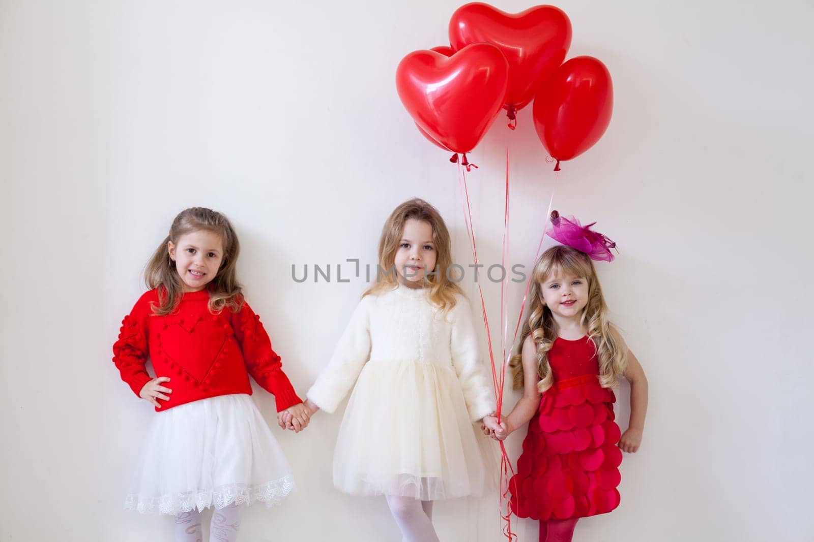 Three little beautiful girls in red hold hands by Simakov