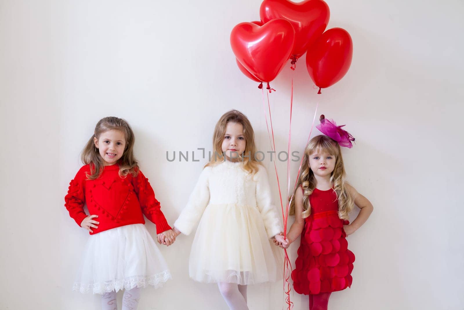 Three little beautiful girls in red hold hands by Simakov