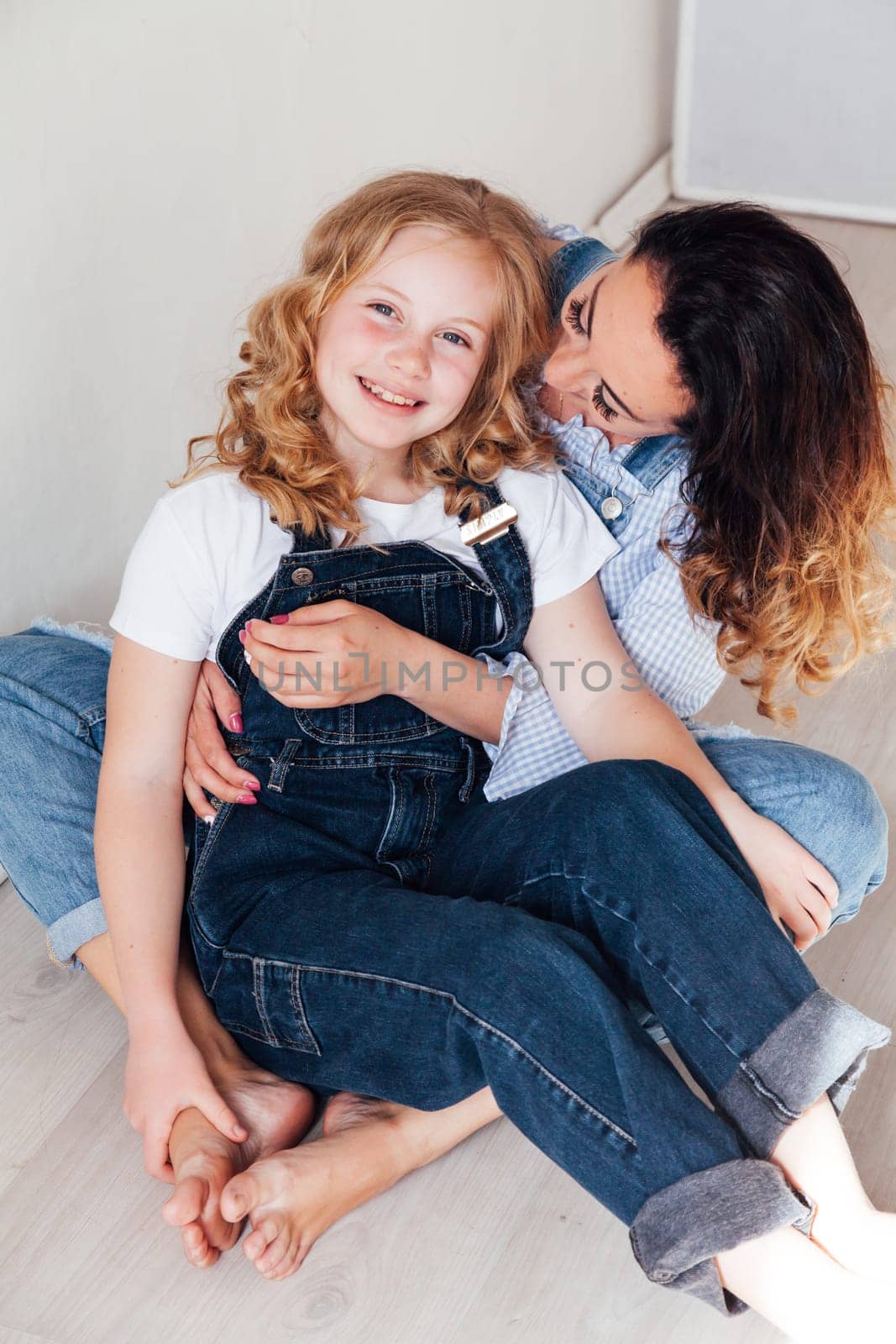 Mom and daughter play cuddles at home on the floor by Simakov