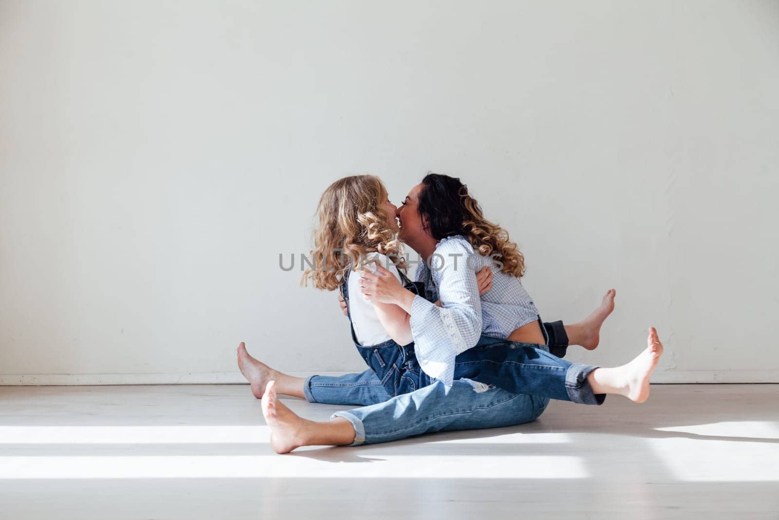 Mom and daughter play cuddles at home on the floor by Simakov