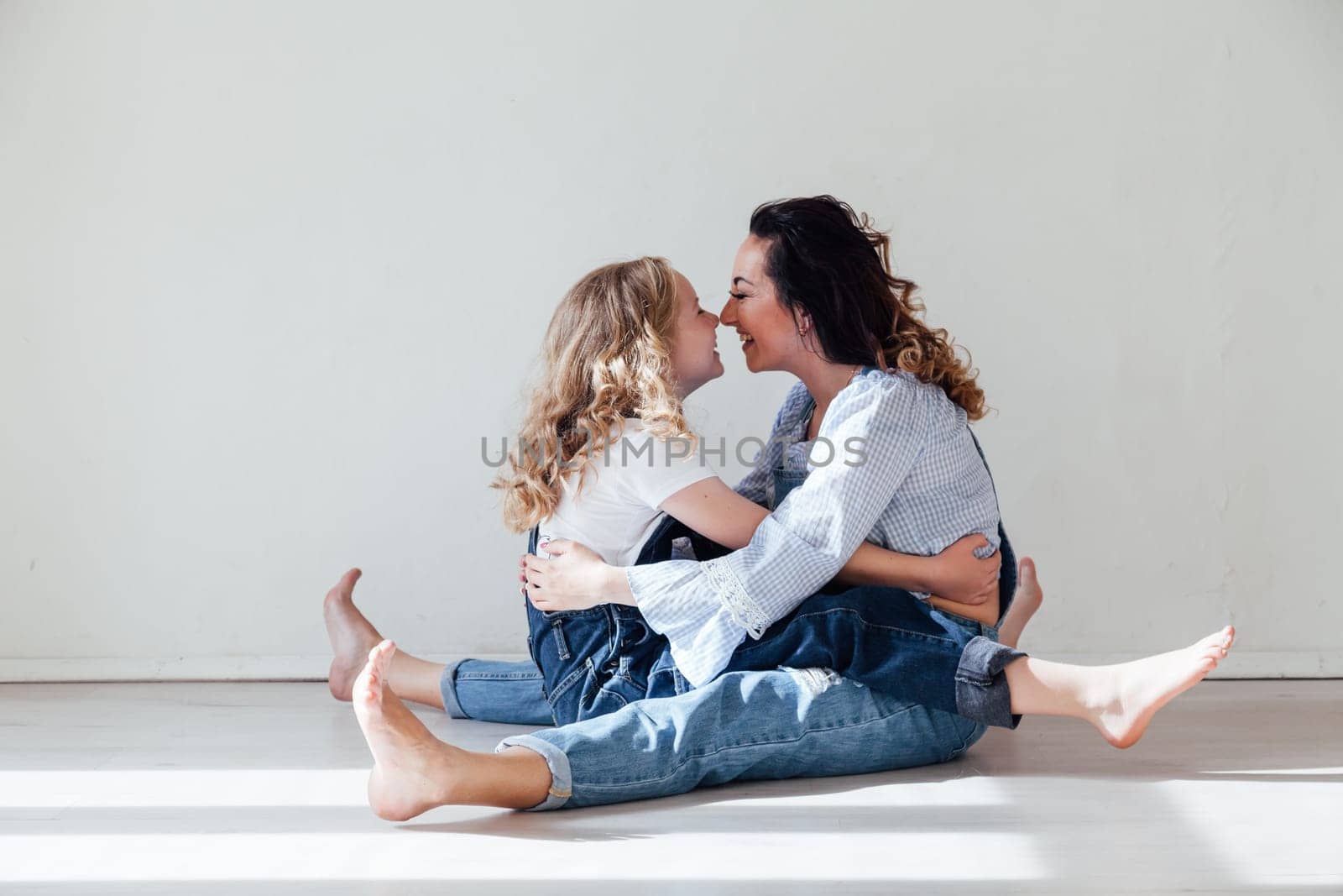 Mom and daughter play cuddles at home on the floor by Simakov