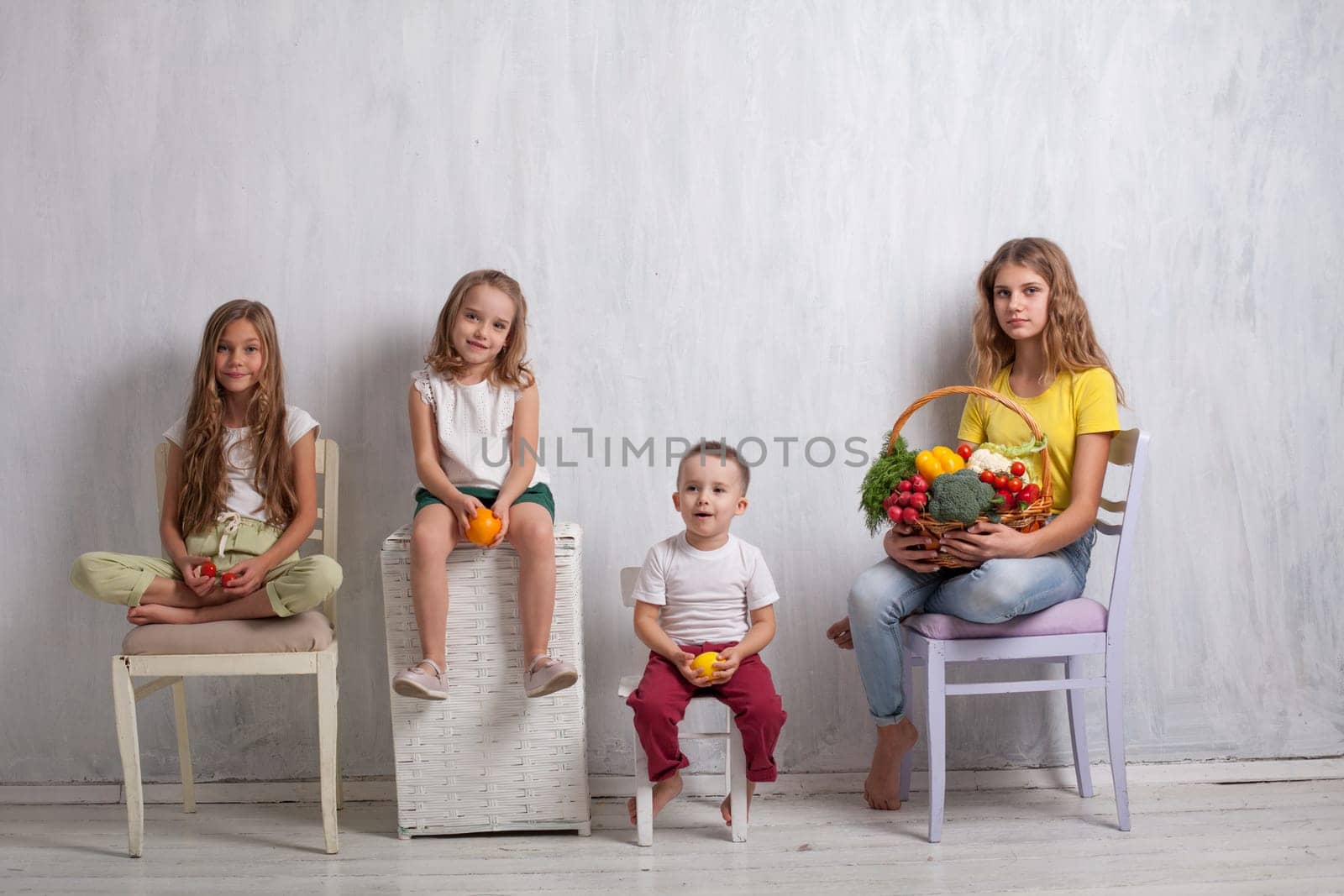Girls and boy hold vegetables and fruits