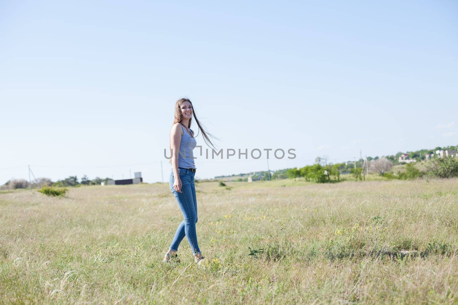 woman walks in a field in the park and smiles