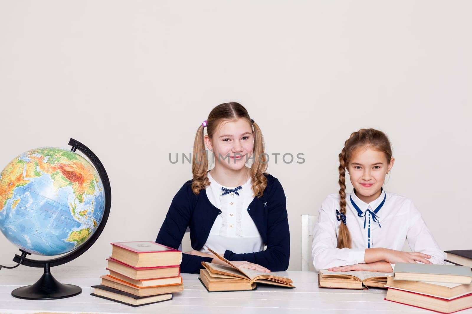 two schoolgirl girls at the desk in a geography class by Simakov