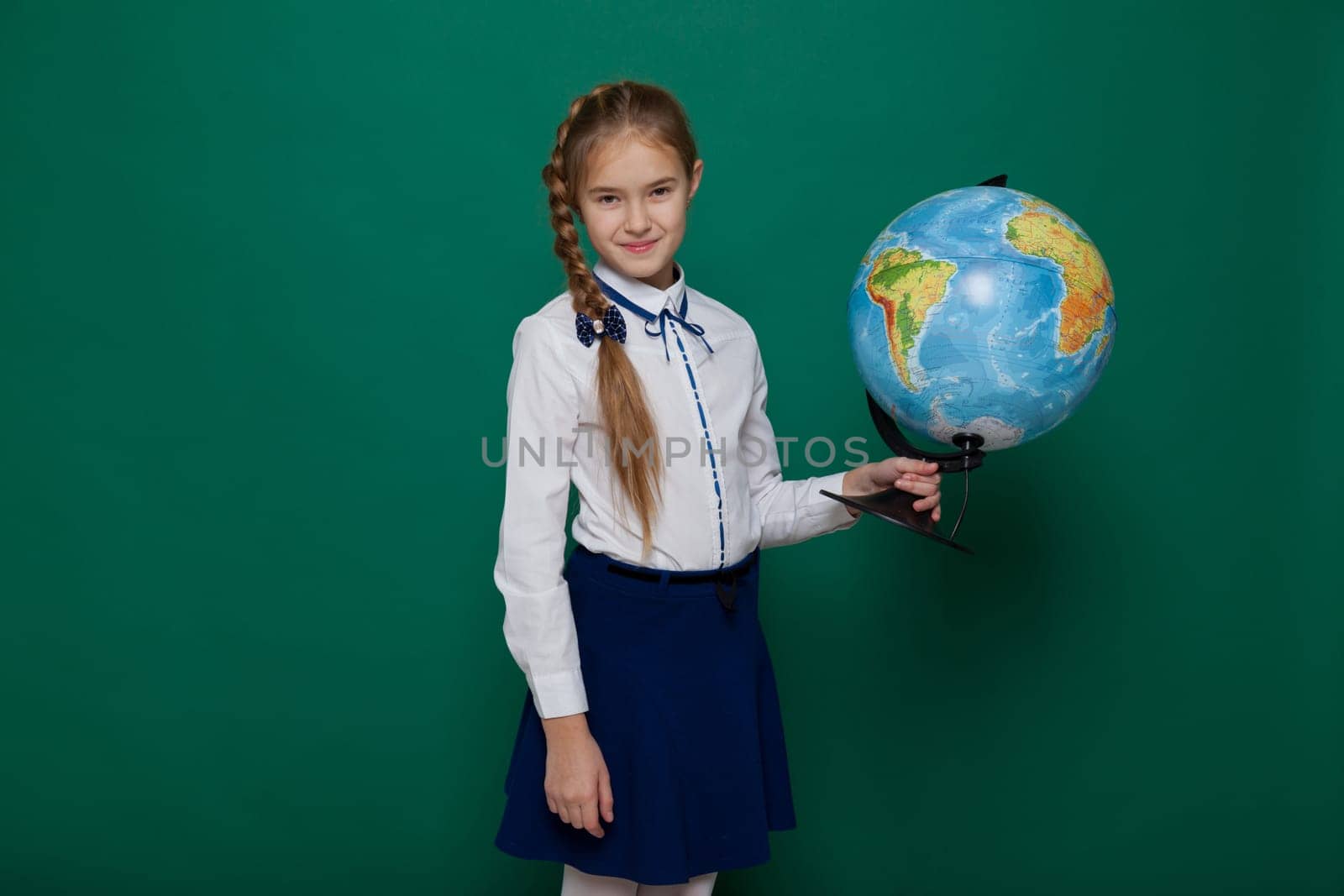 Schoolgirl girl studies globe at school on geography by Simakov