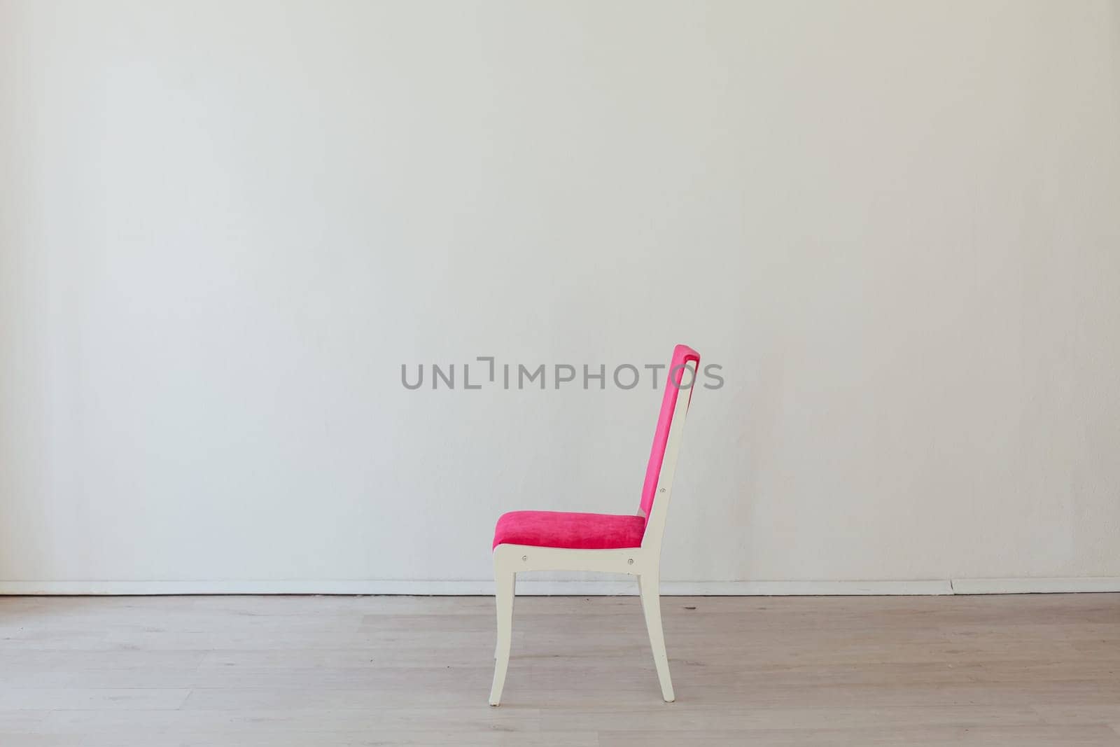 pink chair stands alone in the white room by Simakov