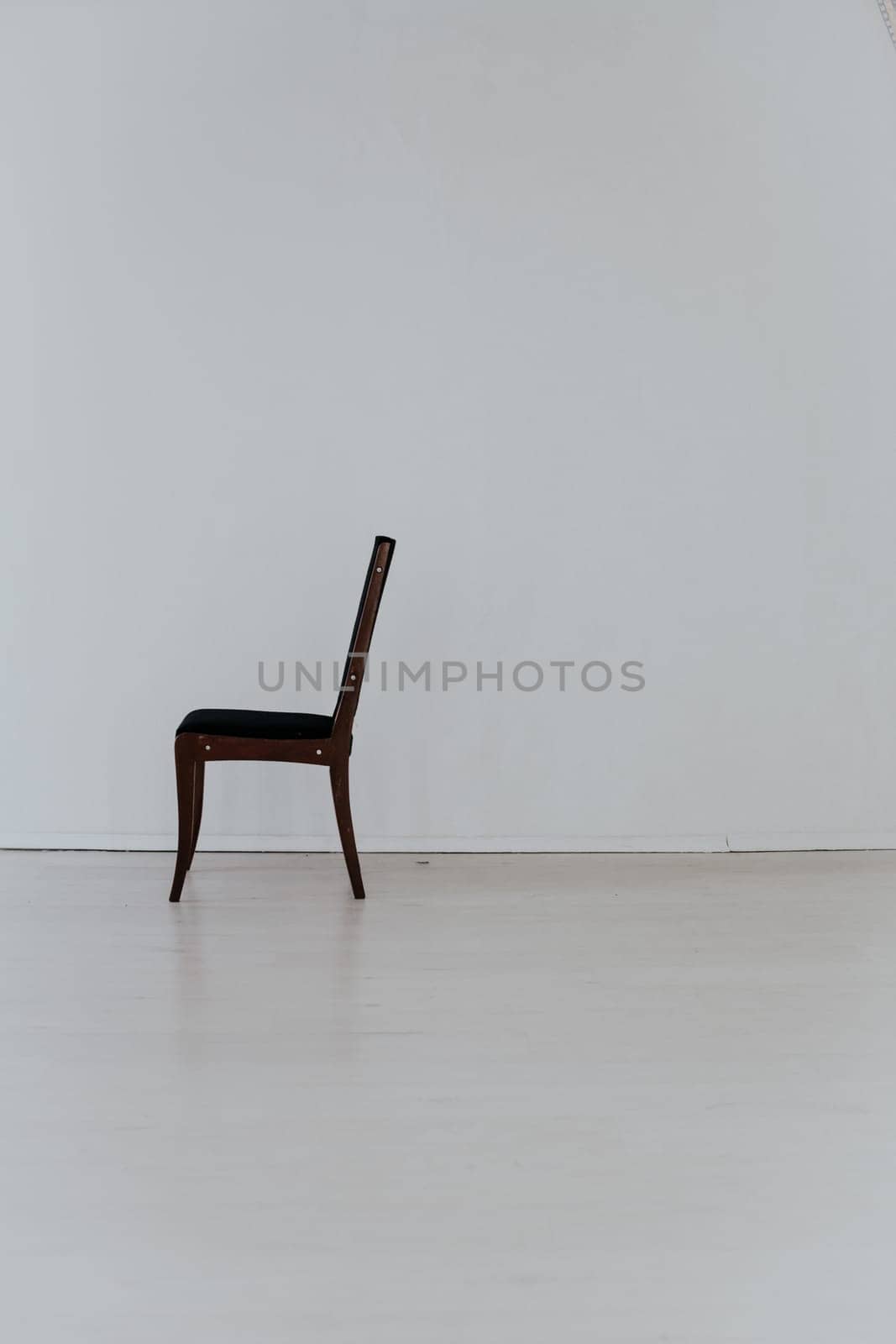 black chair stands alone in the white room by Simakov
