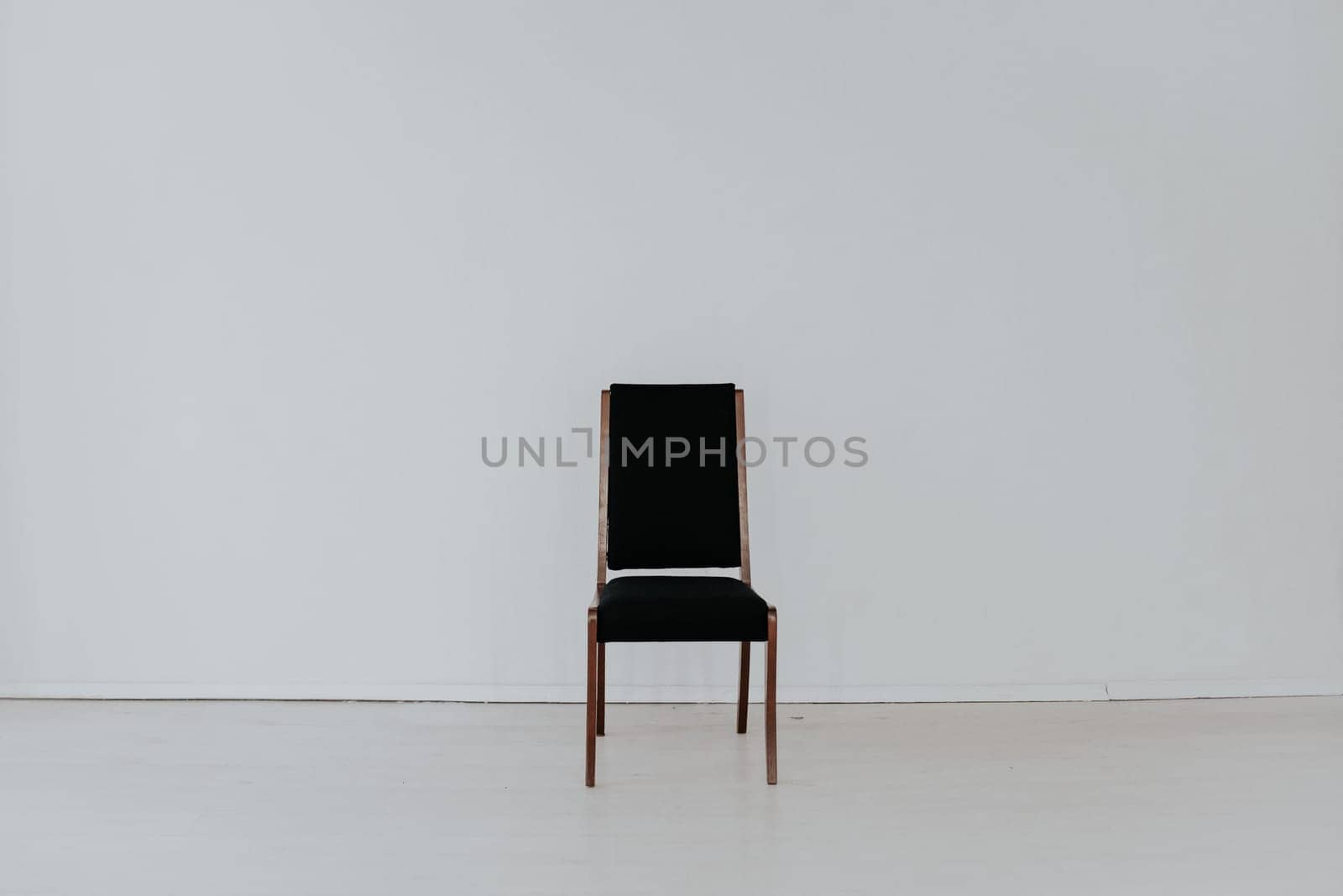 black chair stands alone in the white room by Simakov