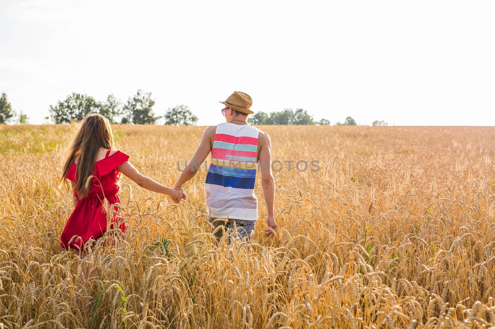 Loving couple holding hands while walking at sunset.