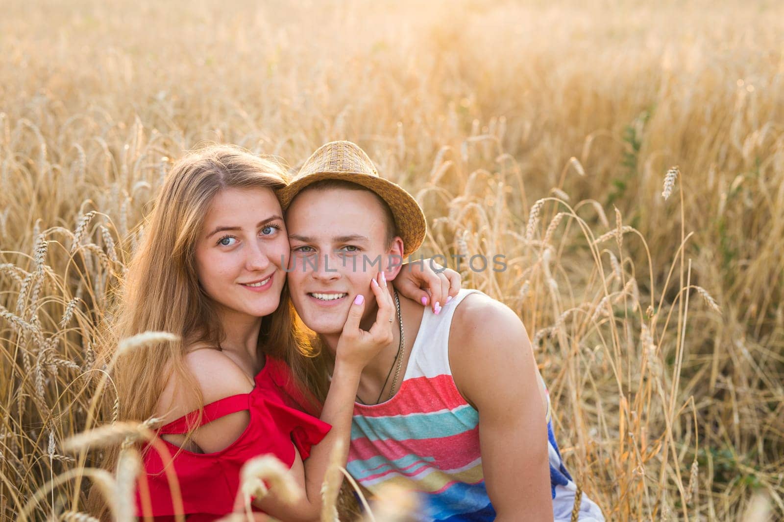 Happy outdoor portrait of young stylish couple in summer in field.
