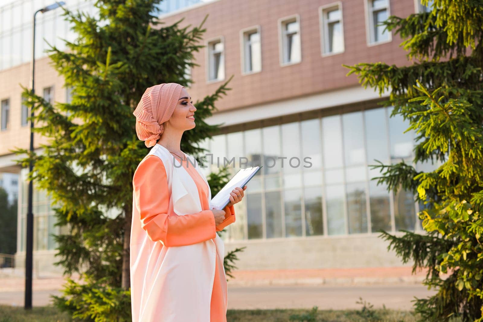 Young Muslim woman standing , holding document paper