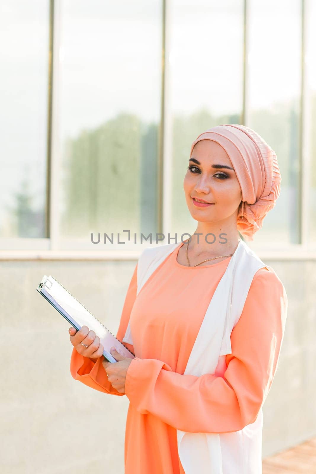 Young Muslim woman standing , holding document paper