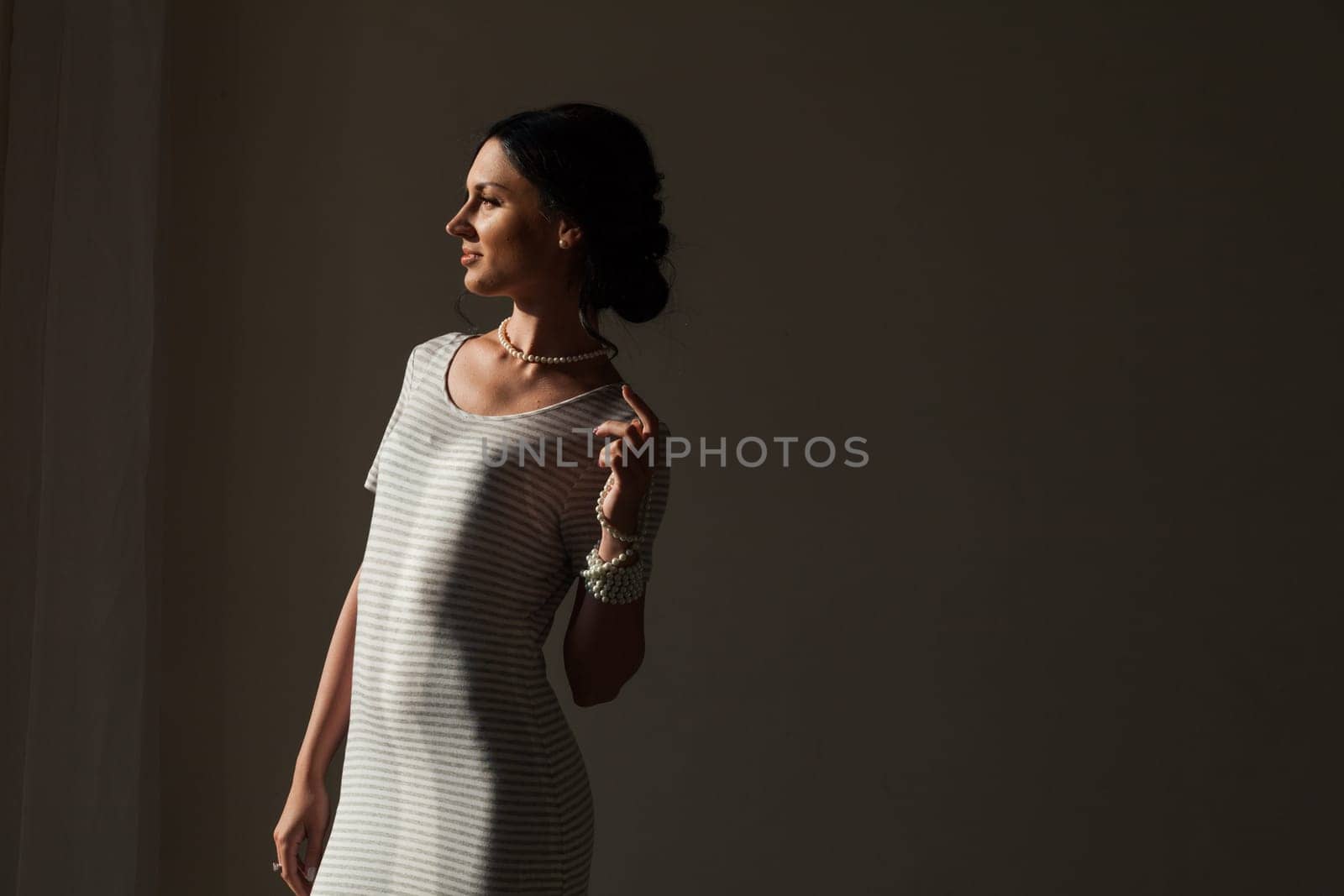 Portrait of a beautiful brunette woman in a striped dress by Simakov