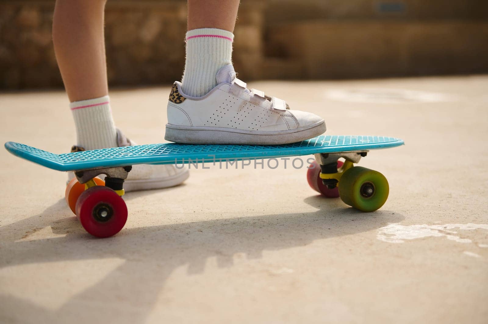 Standing on skateboard on one leg. Close up view of a little child girl legs in blue shoes. by artgf