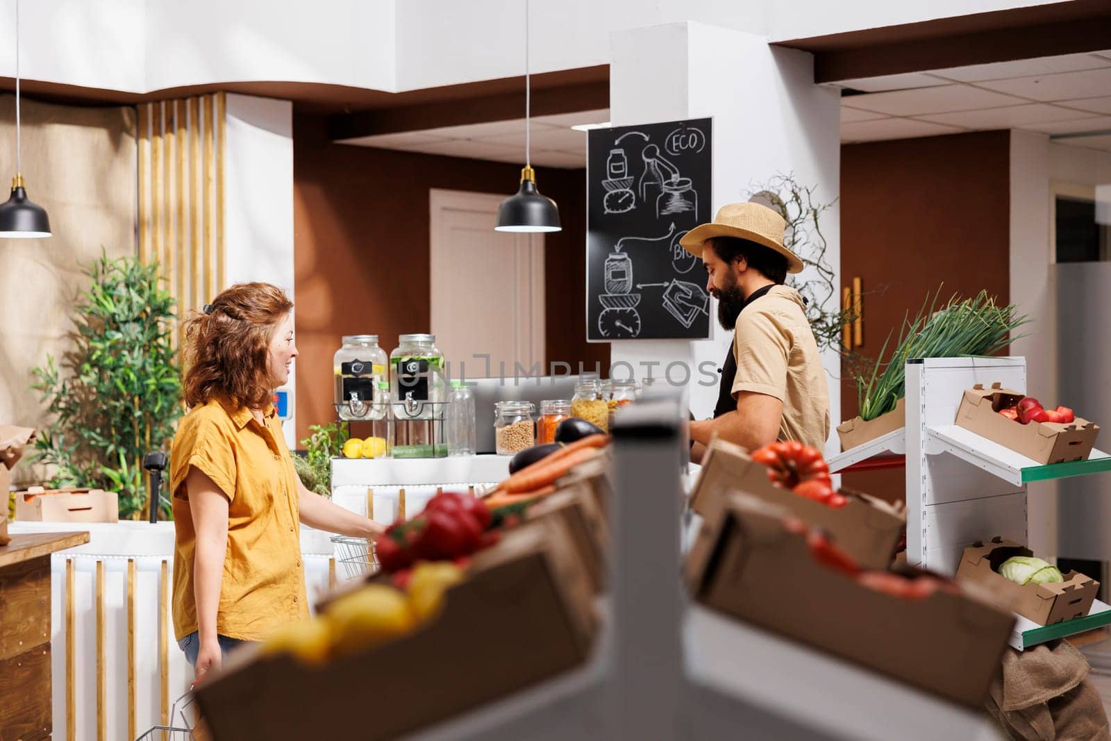 Man and woman in zero waste store filling shopping baskets with healthy locally sourced vegetables. Environmentally responsible clients buying organic pesticides free food from local neighborhood shop