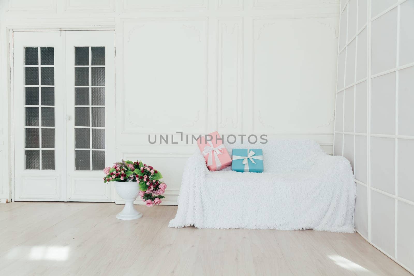 sofa in the interior of the white room with blue and pink gifts for the surprise by Simakov