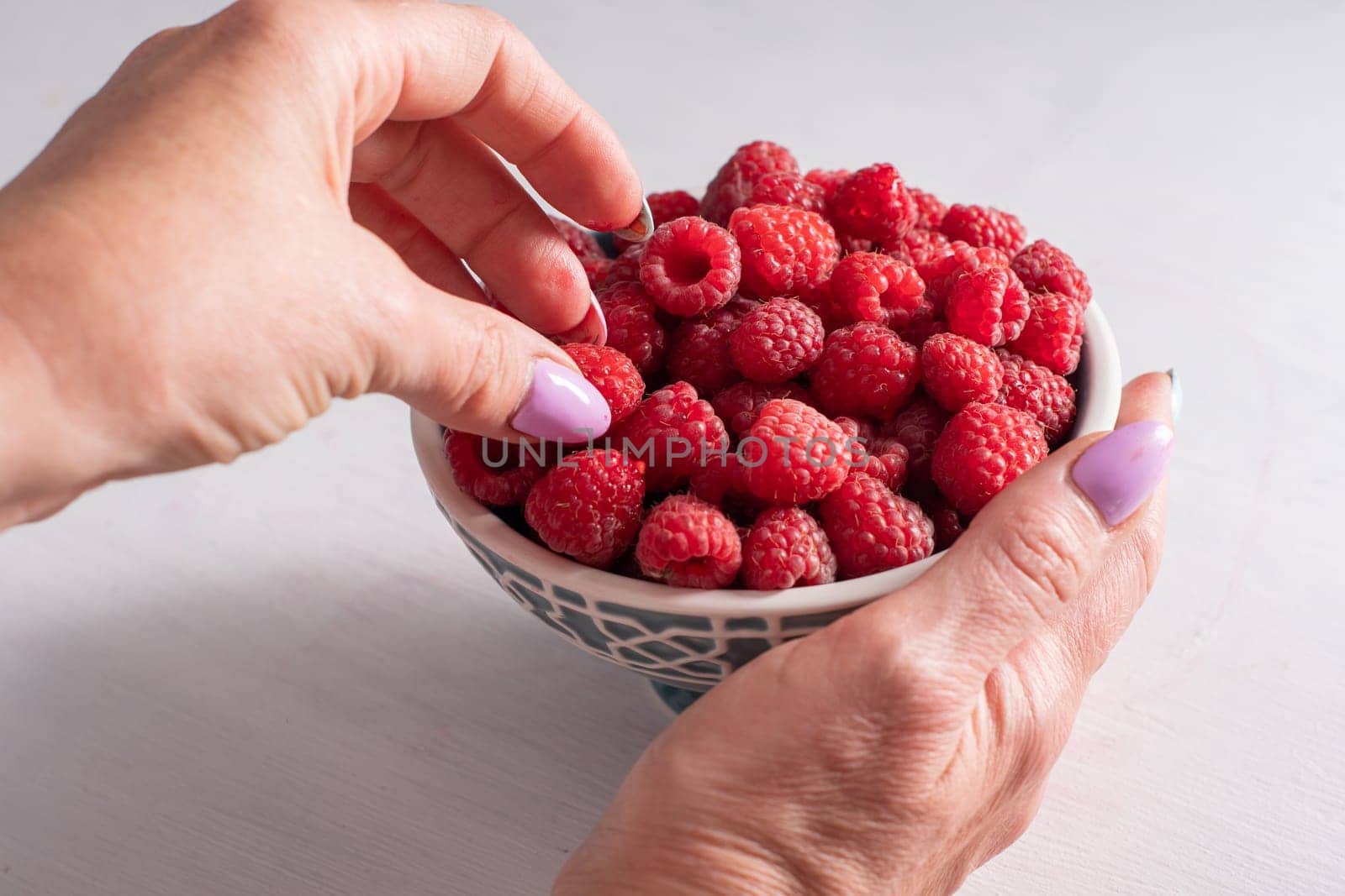 fresh raspberries in a bowl in woman hands, summer harvest fruits and fresh berries, vitamins, vegetarian concept, High quality photo