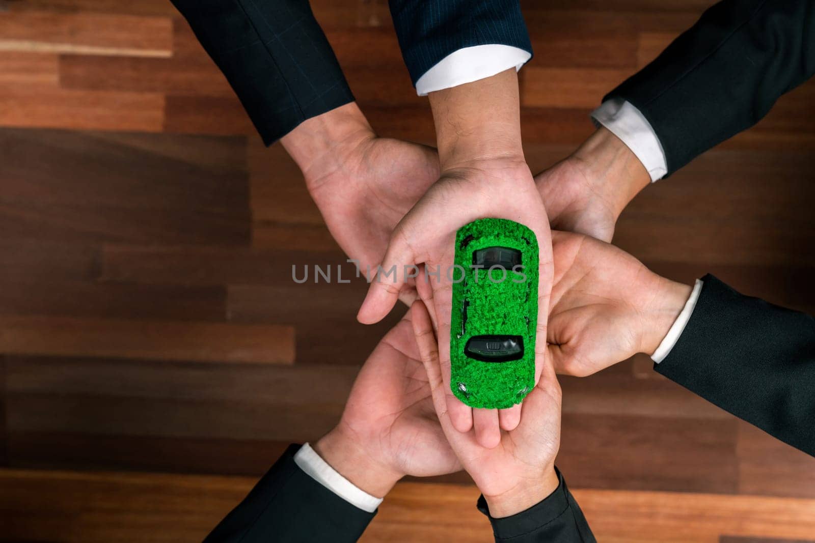 Top view business people holding EV car model as business synergy partnership unite and take action to utilized eco-transportation to reduce CO2 emission for sustainable and greener future. Quaint