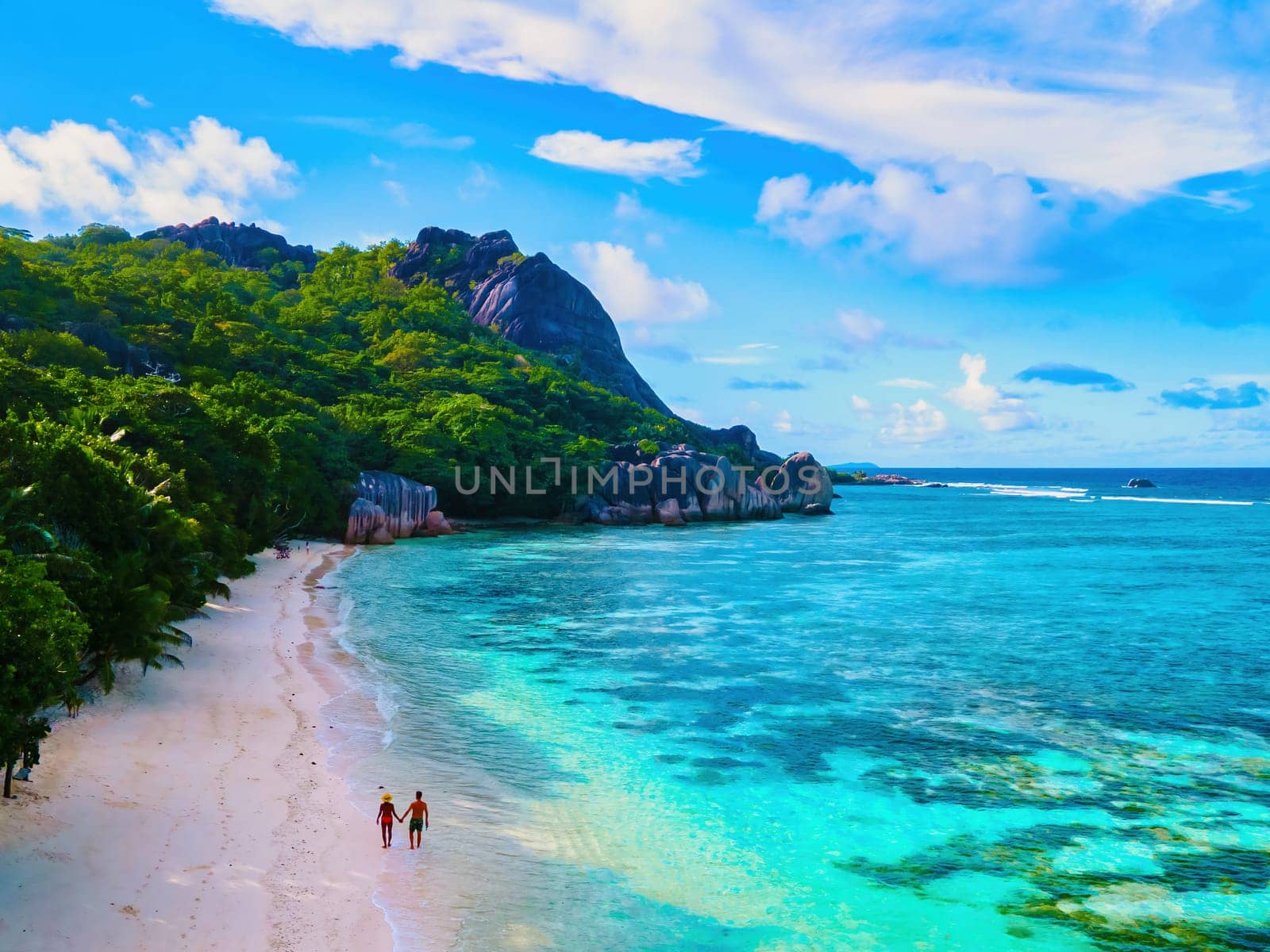 Anse Source d'Argent beach, La Digue Island, Seychelles, couple men and woman walking at the beach during sunset at a luxury vacation at the tropical Islands of Seychelles