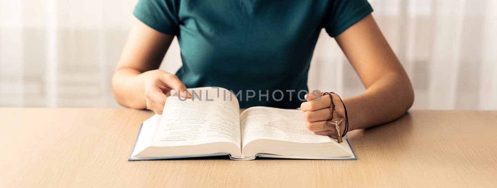 Female believer reads holy bible faithfully while holding cross at light wooden church. Concept of hope, religion, faith, believe, christianity, catholic and god blessing. Front view. Burgeoning.