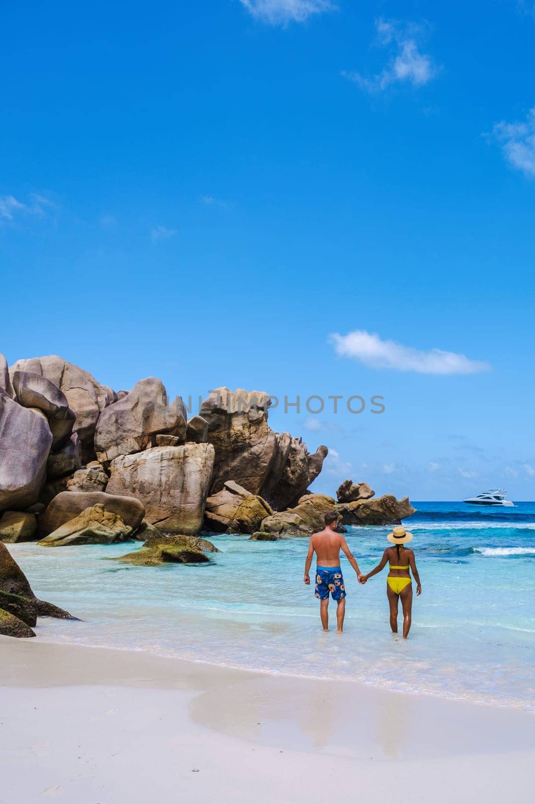 Anse Cocos beach La Digue Island, Seychelles, diverse mixed multiracial couple Caucasian men and Asian woman walking at the beach during sunset