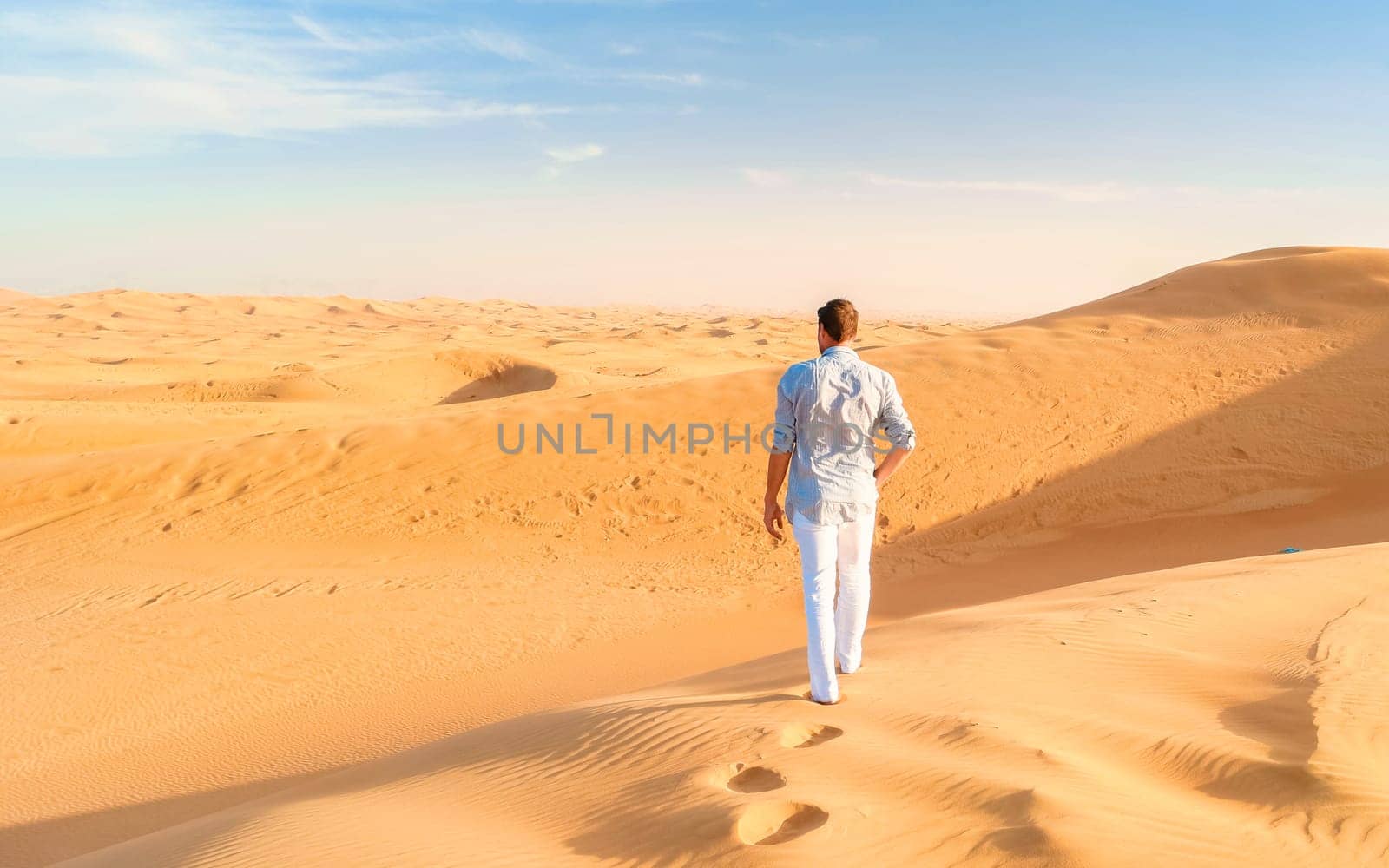 Young men walking in the desert of Dubai, Sand dunes of Dubai United Arab Emirates by fokkebok