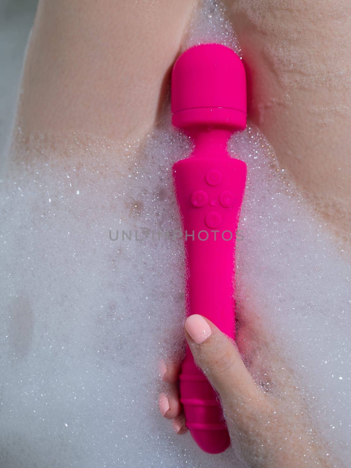 Woman lies in a bubble bath and uses a vibrator