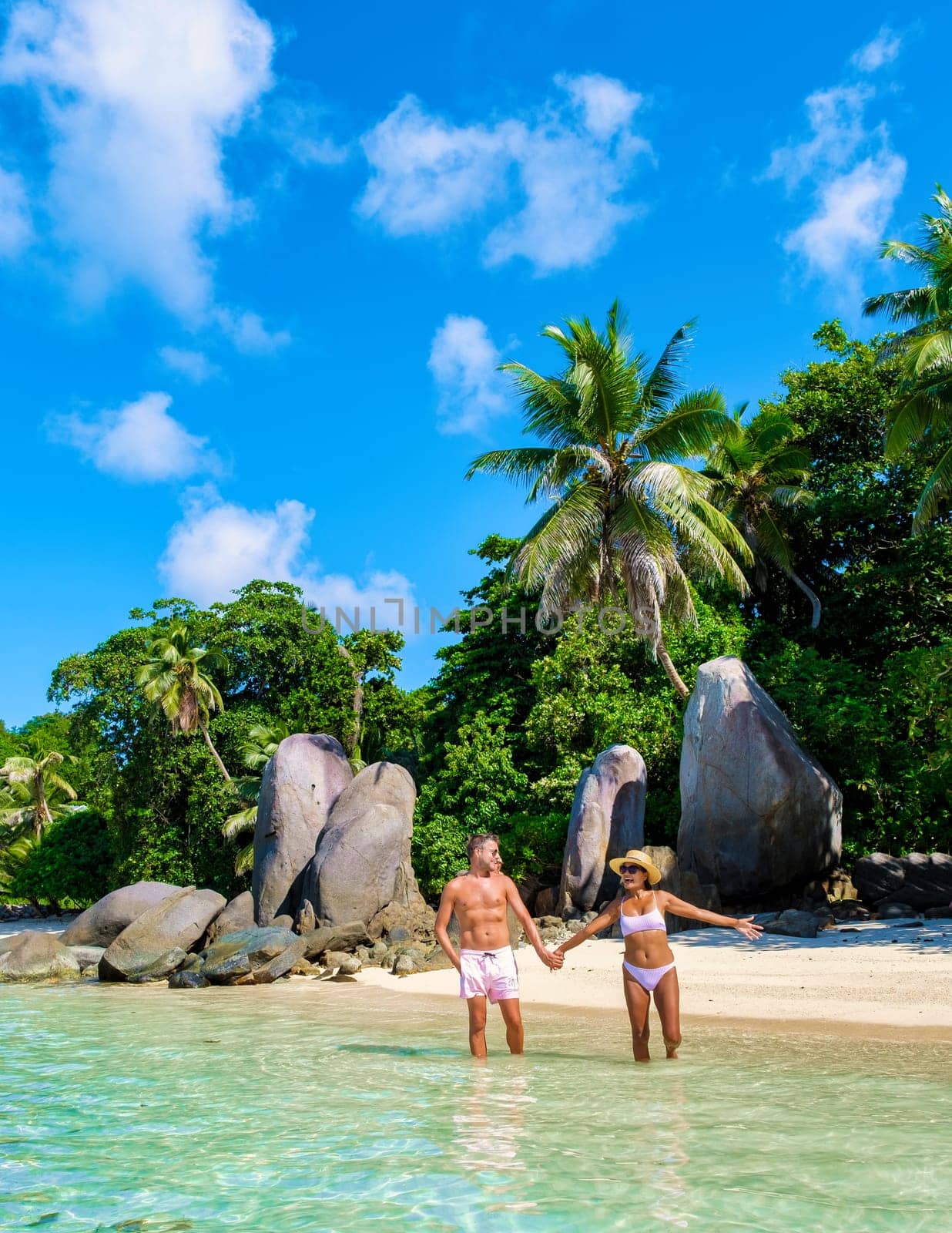 Anse Royale beach, a couple of men and women on vacation in Seychelles walking at the beach, Mahe Seychelles tropical beach with palm trees and a blue ocean